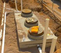 In-ground grease interceptor installation showing concrete access lids with risers and PVC pipe connections - large capacity outdoor grease trap for commercial kitchens